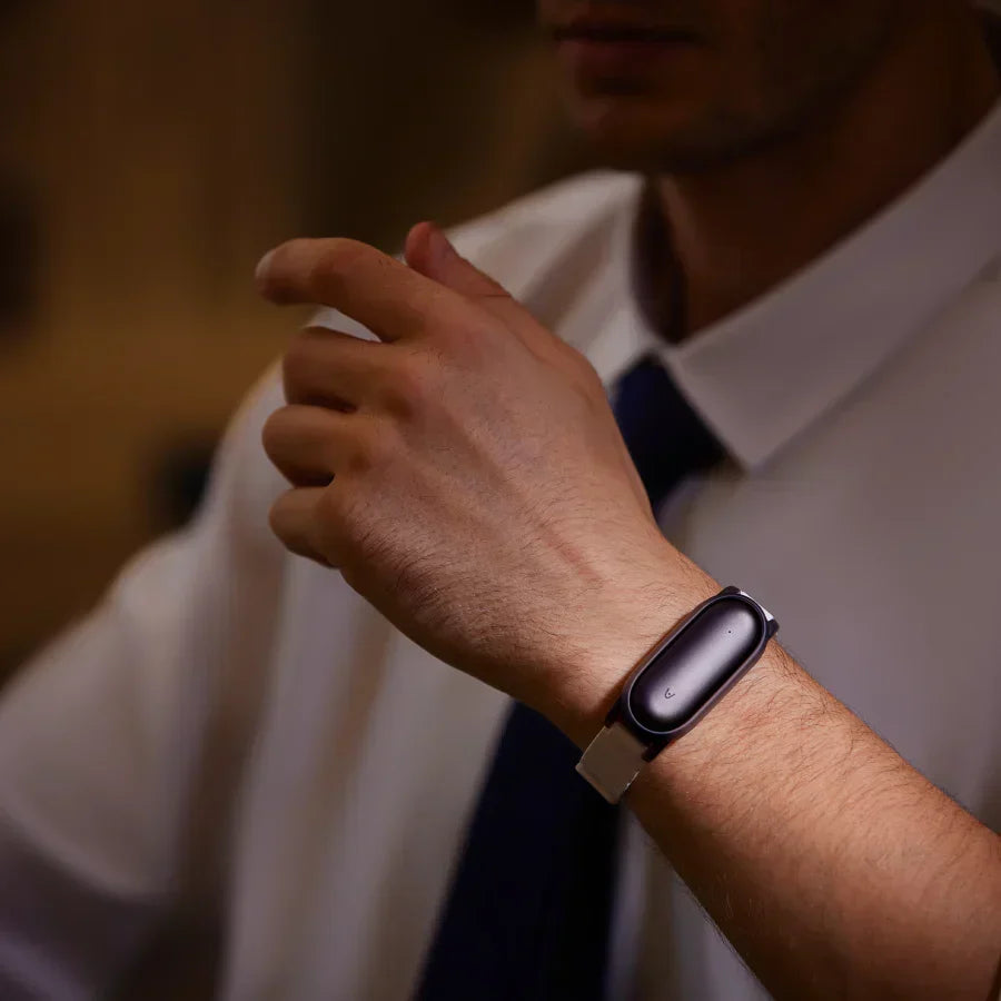 Man wearing a black Plaud NotePin on a silver wristband, paired with professional attire.