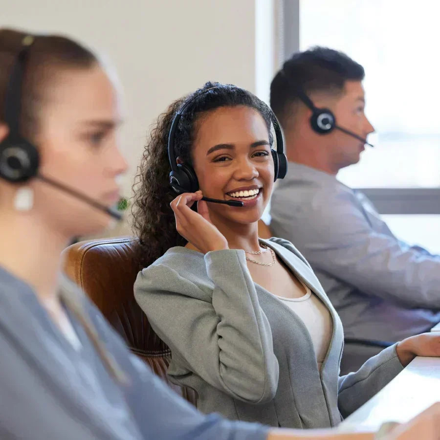 Smiling customer support representative wearing a headset in an office.
