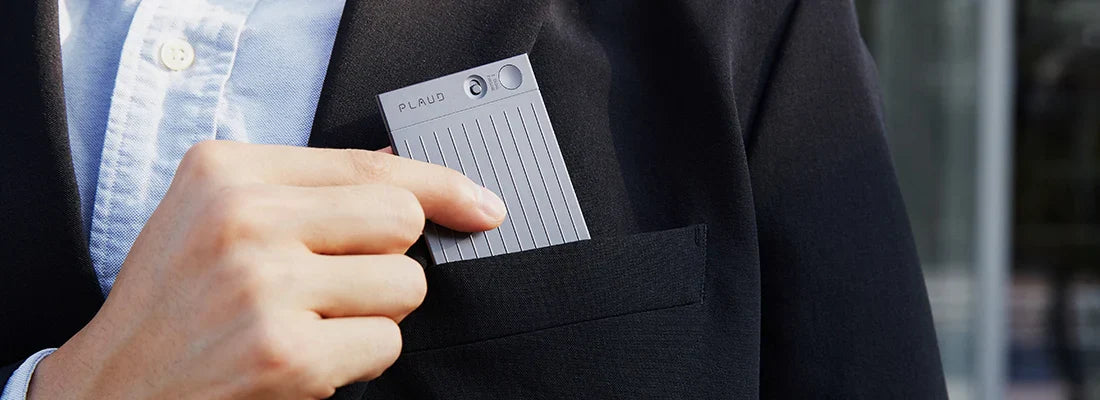 Person placing a gray Plaud Note Pro into a suit jacket pocket.
