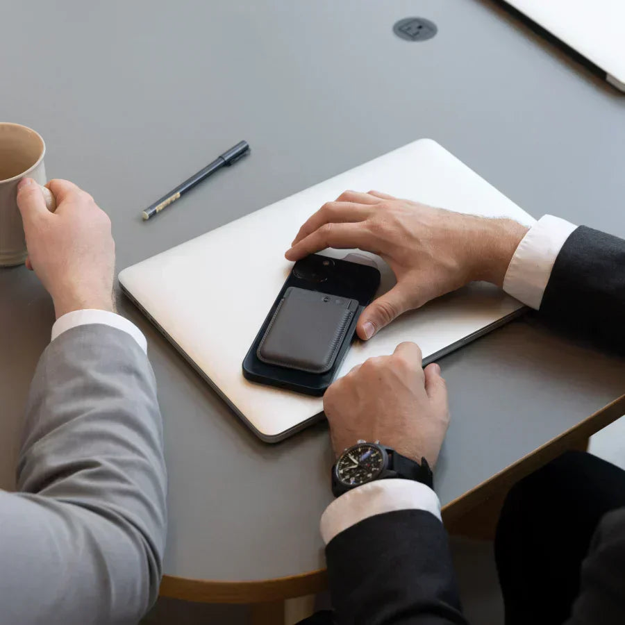 Black Plaud Note attached to a smartphone on a desk during a business meeting.