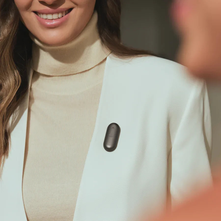A woman wearing a Cosmic Gray Plaud NotePin on the lapel of her white blazer.
