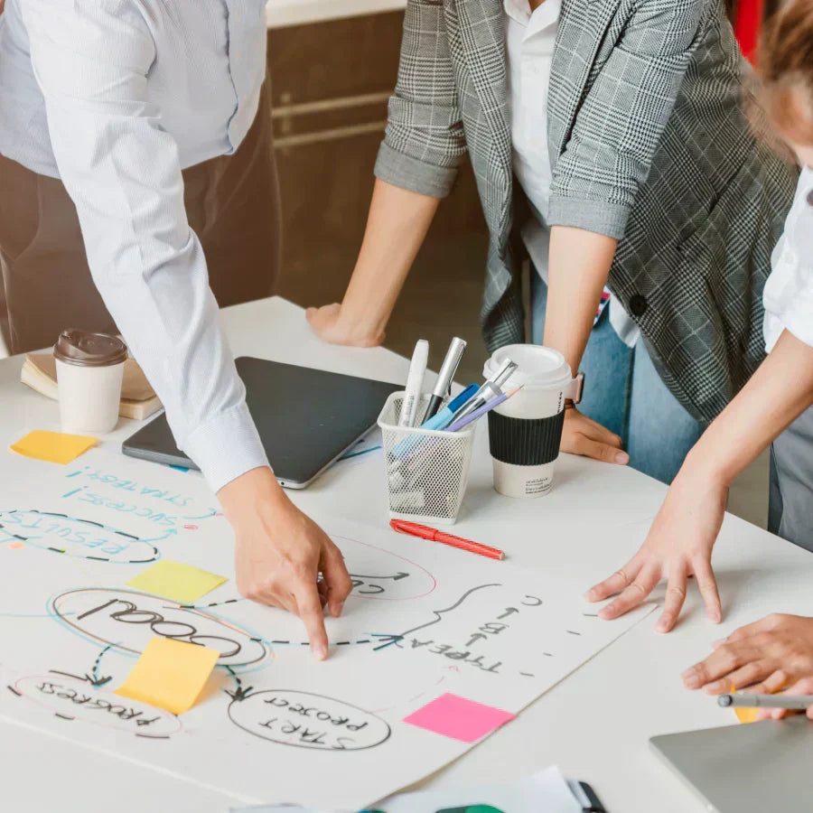 A team collaborates on a project plan while a member wears a white Plaud NotePin on their wrist to record the meeting.