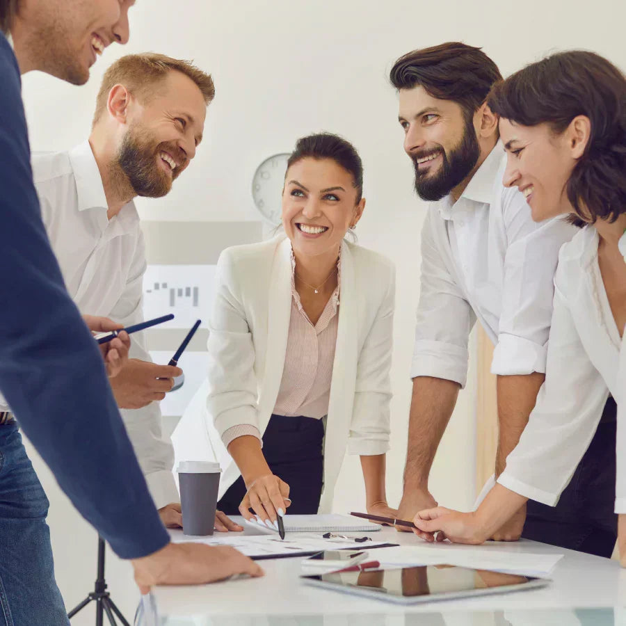 A smiling team of professionals collaborates around a table during a business meeting in a bright office.