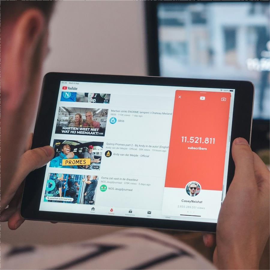 ALT attribute: A person holding a tablet displaying YouTube with a channel's subscriber count.