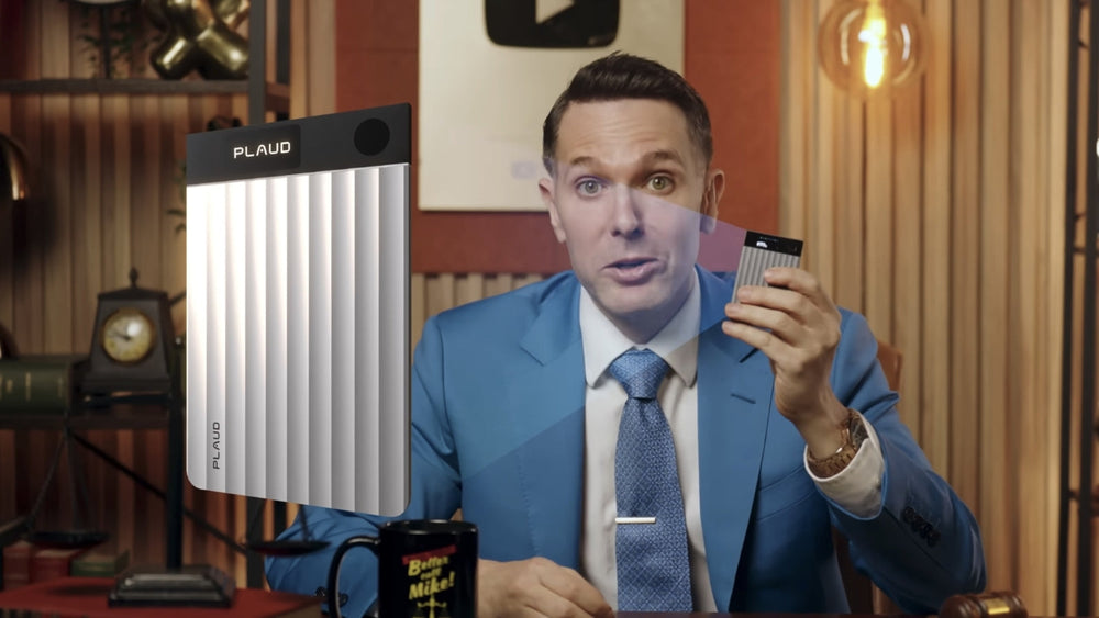 Man in a blue suit holds a silver Plaud Note Pro with a ribbed body and screen.