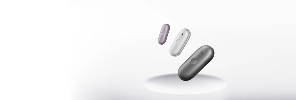 Three Plaud NotePin wearable AI voice recorders in purple, silver, and gray floating above a white pedestal.