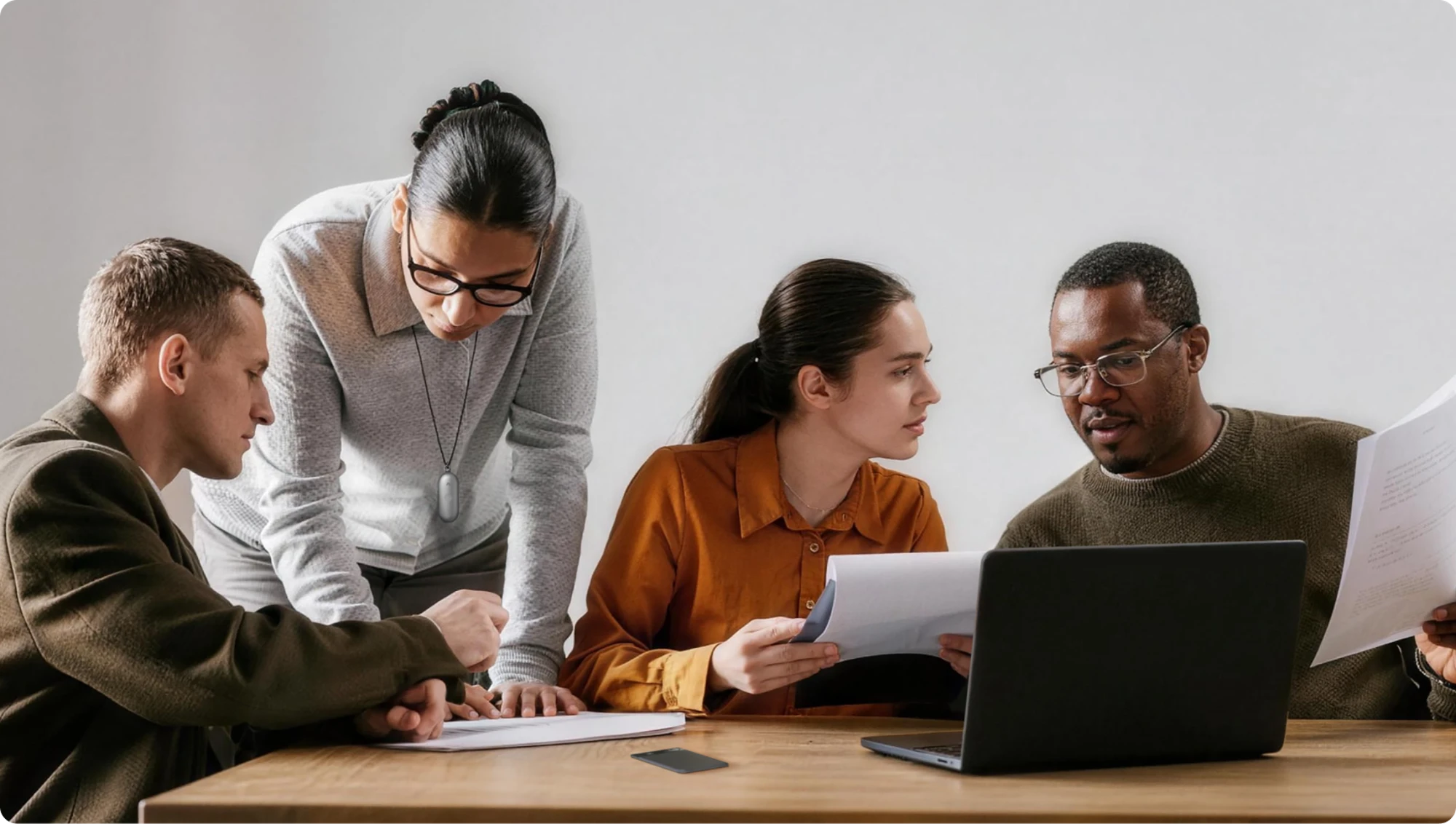 Professionals collaborating with a grey Plaud NotePin on a lanyard and a black Plaud Note on the table.