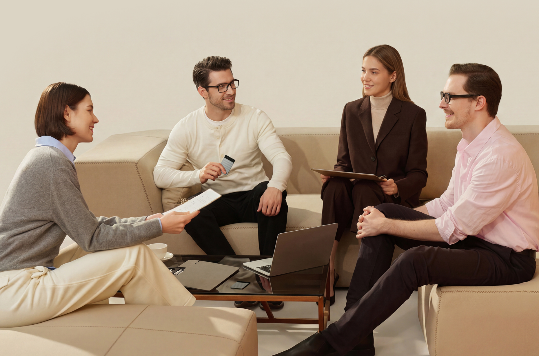 Four professionals sit on a beige couch for a meeting as one man holds a silver Plaud Note Pro AI voice recorder.